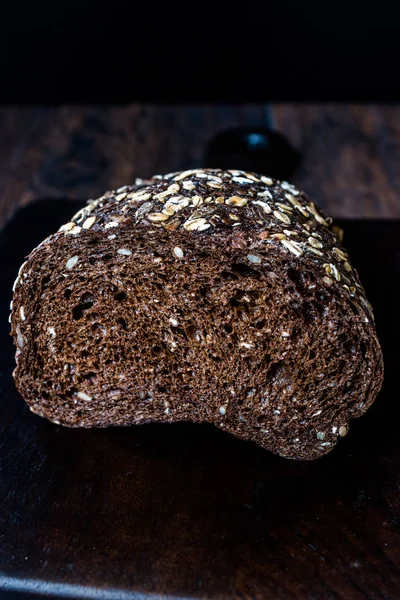 Malt Bread Slices with Oat and Flax Seeds on Dark Wooden Board.