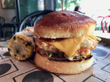 Fast Food Restaurant'ta Tepside Cheddar Peyniri, Mısır ve Coleslaw ile Zinger Çıtır Tavuk Burger.