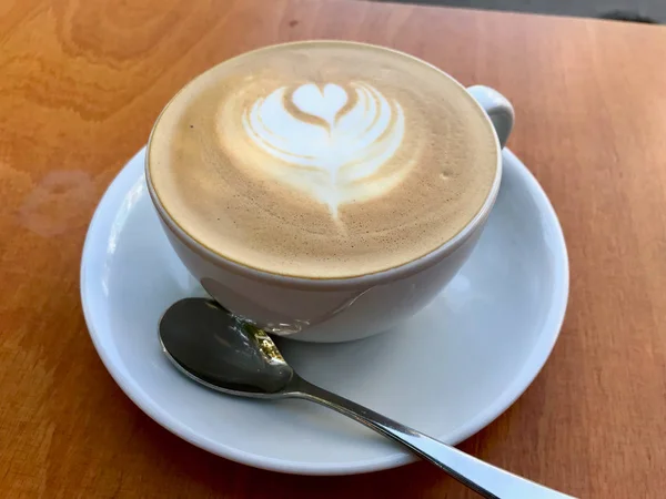 Taza de café con leche plana blanca en la mesa de madera en la cafetería . — Foto de Stock