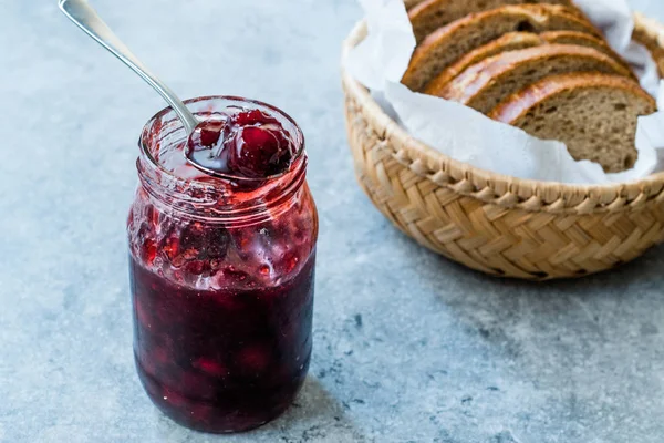 Confiture de canneberges en pot avec cuillère / confiture de canneberges servie avec tranches de pain dans un bol en osier . — Photo