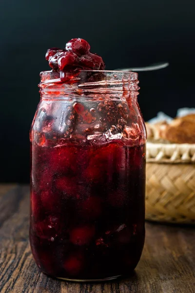 Confiture de canneberges en pot avec cuillère / confiture de canneberges servie avec tranches de pain dans un bol en osier . — Photo