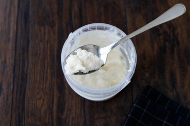 Stracciatella Mozzarella Peyniri Plastik Konteyner Kupası 'nda, kaşıkla. Yemeye ve Kullanmaya Hazır.