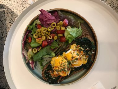 Floransa usulü yumurta, haşlanmış yumurta, ıspanak ve leziz tereyağlı Hollandaise soslu salata ve Cafe Restaurant 'ta yeşil zeytin dilimleri..