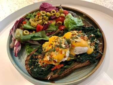 Floransa usulü yumurta, haşlanmış yumurta, ıspanak ve leziz tereyağlı Hollandaise soslu salata ve Cafe Restaurant 'ta yeşil zeytin dilimleri..