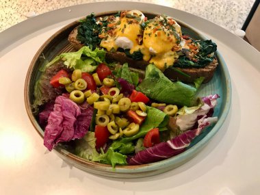 Floransa usulü yumurta, haşlanmış yumurta, ıspanak ve leziz tereyağlı Hollandaise soslu salata ve Cafe Restaurant 'ta yeşil zeytin dilimleri..