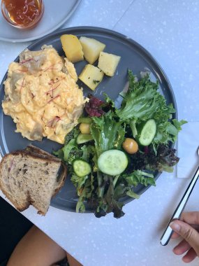 Cafe Restoran 'da çırpılmış yumurta, mantar, kruvasan, ekşi ekmek ve salata ile kahvaltı tabağı.