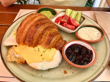 Kruvasan sandviçli haşlanmış yumurta ve reçelli Hollandaise sosu. Restoranda yoğurt ve marmelat..