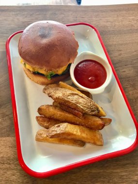 Tahta Masa 'daki Fast Food Restaurant' ta patates tabağıyla hamburger menüsü servis ediyorum. Yemeye hazır..