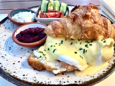 Restoranda servis edilen kahvaltı tabağında Hollandaise soslu kruvasan haşlanmış yumurta Benedict ve somon gravlax. Yemeye hazır..