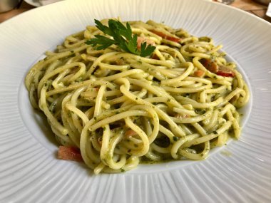 Restorandaki büyük tabakta pesto soslu yeşil spagetti. Hizmet ve Yemeye Hazır.