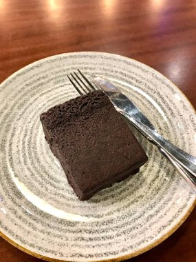 Plate Fork and Knife 'deki kafe' de servis edilen badem unuyla pişirilmiş glütensiz ve şekersiz çikolatalı unsuz kek. Yemeye hazır..