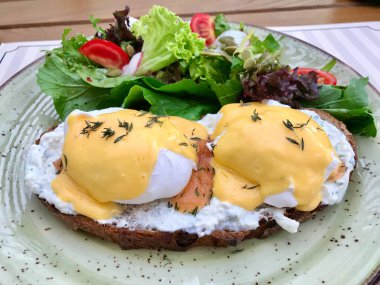 Somon Gravlax 'lı haşlanmış yumurta, Hollandaise sosu, Ekşi hamurlu mayonezli ekmek ve kahvaltı için salata. Organik Gıda.