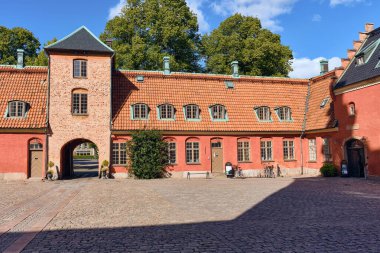 Halmstad, İsveç 'in başkenti Halmstad' da tarihi Halmstad şatosunun avlusunda kırmızı tuğla duvarlar, kiremitli çatılar ve parçalı bulutlu gökyüzü altında bir kule..