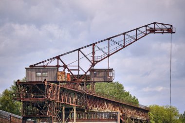 Peenemuende, Almanya; 25 Haziran 2019: Peenemunde enerji santrali kıyı sahasında eski paslı vinç yapısı, görünür sanayi detayları ile bulutlu yaz gökyüzü altında fotoğraflandı.