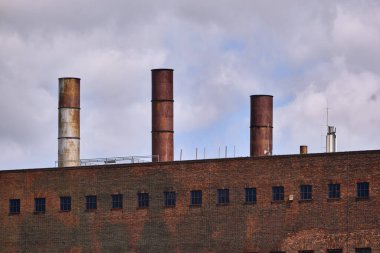 Peenemuende, Almanya; 25 Haziran 2019: Peenemunde 'de tarihi cephe üzerinde yükselen dört paslı bacası olan sanayi tuğla santrali, yaz bulutları altında miras kıyı mimarisi olarak fotoğraflandı.