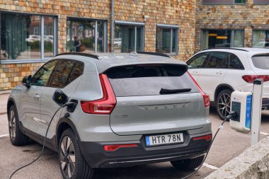 Karlskrona, İsveç; 14 Eylül 2025: EV hareketliliğini ve yenilenebilir enerjiyi sembolize eden Mercedes EQB 'nin yanındaki istasyonda elektrik Volvo XC40 yeniden şarj patlayıcıları.