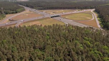 Yüksek açılı insansız hava aracı birden fazla şeritli ve üstgeçitli geniş bir otoyol kavşağını yakalıyor. Geniş yol ağı geniş çam ormanları ve açık çim alanlarıyla çevrilidir..