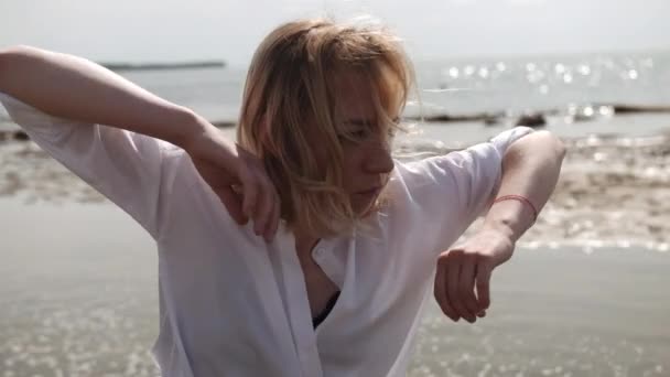 Blond meisje sensueel dansen op een achtergrond van de zee in witte kleren — Stockvideo