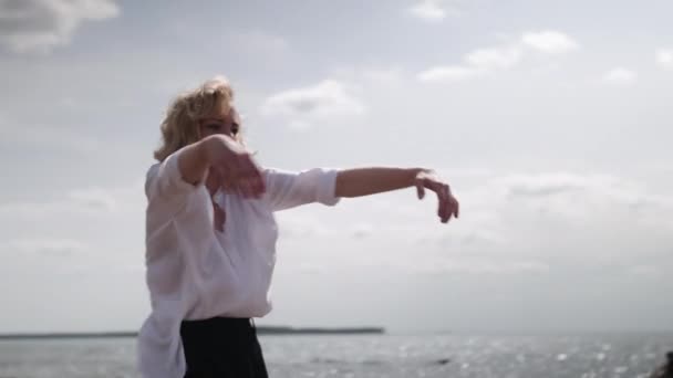 Blonda fata senzual dans pe un fundal al mării în haine albe și negre — Videoclip de stoc
