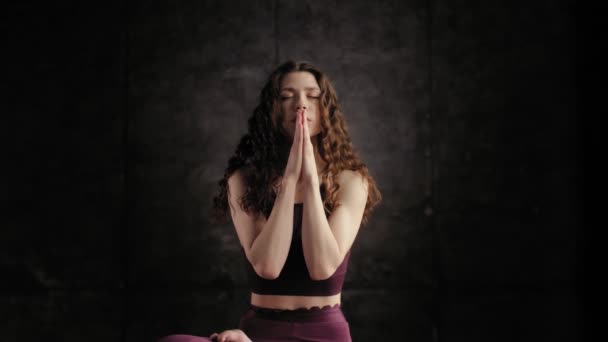 ผู้หญิงในชุดสีม่วงสดใสกําลังทําสมาธิและมองไปที่กล้อง ป้าย Namaste — วีดีโอสต็อก