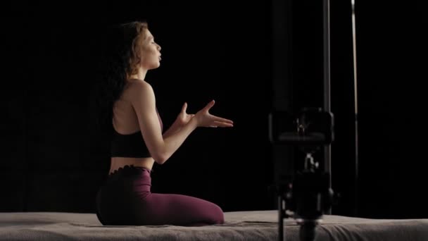 A young girl in lilac sportswear conducts an online yoga class. Takes a picture of himself on a cell phone — Stock Video