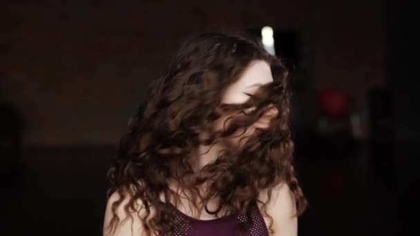 Chica blande el pelo. Primer plano de la chica que blande hermoso pelo rizado en la cámara y sonríe — Vídeo de stock