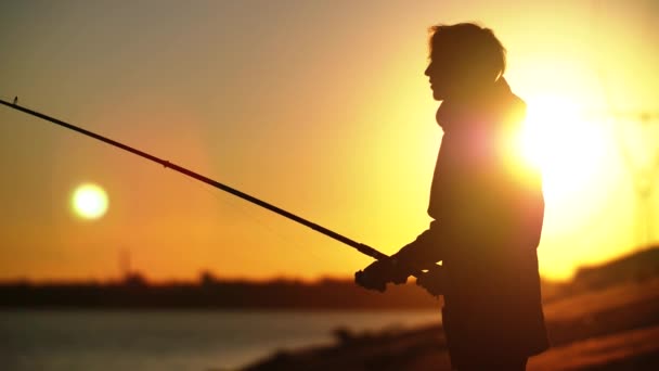 Gemiddelde visser plan met hengel tegen zonsondergang — Stockvideo