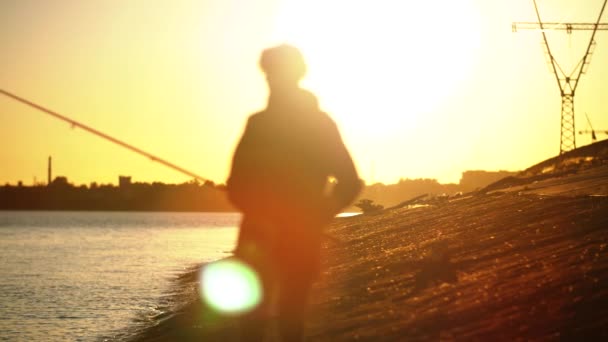 Εναλλαγή εστίασης από το τοπίο στη σιλουέτα ενός ψαρά που στέκεται απέναντι στο ηλιοβασίλεμα — Αρχείο Βίντεο