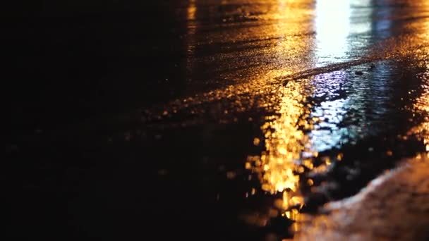 Skup się na drodze miejskiej. Pozioma panorama asfaltu po deszczu. Samochody przechodzą i reflektory odbijają się na kałużach — Wideo stockowe