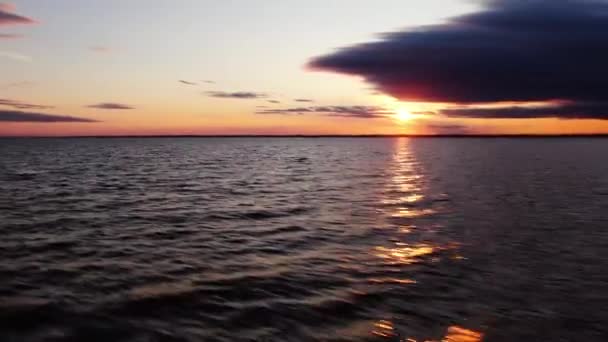 En lang stråle fra den nedgående sol reflekterer over havet i dynamisk bevægelse. Flyver over solnedgangen havet – Stock-video