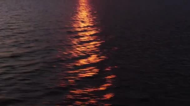 Светлый луч заходящего солнца отражается на темном море. — стоковое видео