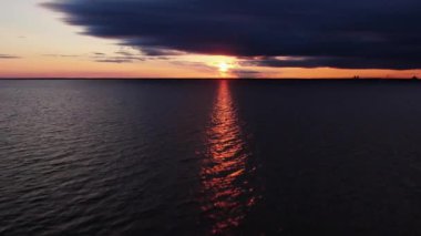 Günbatımının arka planında bir ışık huzmesi olan karanlık deniz.