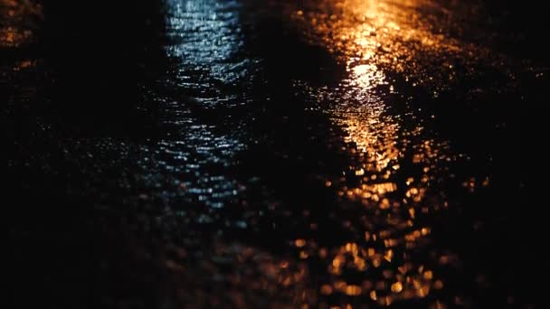 Reflexiones sobre el asfalto de la ciudad nocturna. El agua corre y brilla en la luz de las luces nocturnas — Vídeos de Stock