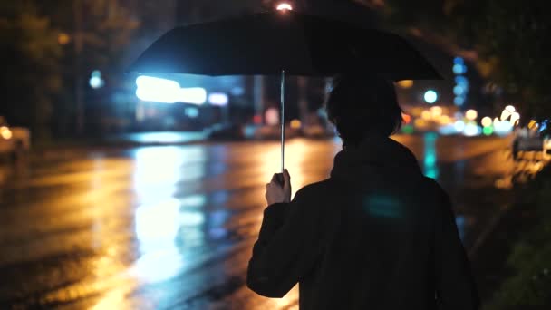 Мужчина стоит с зонтиком на фоне городского пейзажа после дождя — стоковое видео