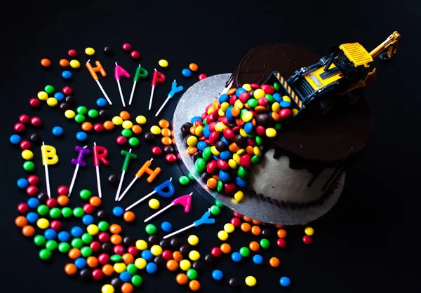 Birthday chocolate cake with tracktor and candy on top. Happy Birthday candles