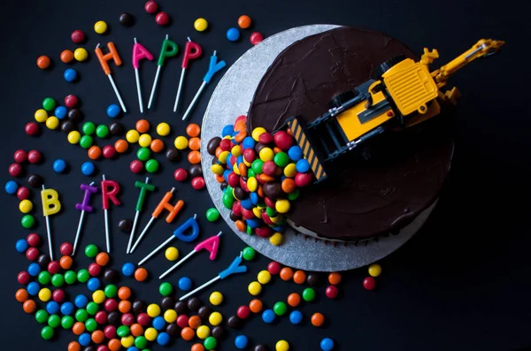 Birthday chocolate cake with tracktor and candy on top. Happy Birthday candles