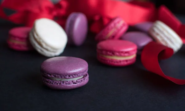 macaroon on black background with red ribbon, colorful almond cookies, pastel colors. Present with love. St.Valentines day