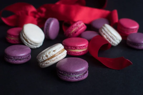 macaroon on black background with red ribbon, colorful almond cookies, pastel colors. Present with love. St.Valentines day