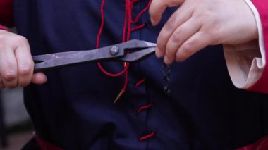 El işleri ve metal işçiliği. El işi, gelenek, el işi. Küçük, karmaşık metal parçalarla çalışmak için iki çift metal pense kullanıyor. Adam geleneksel tarihi kıyafetler giyiyor..
