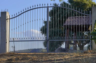 Titreyen tepeleri olan sakin bir İtalyan kırsalı tarafından galvanize edilmiş ve çerçevelenmiş klasik bir demir kapı, barışı koruyor gibi görünüyor..