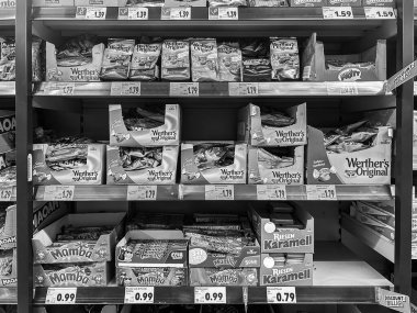 Stuttgart, Almanya - 14 Ağustos 2025: Alman şekerleme mağazası koridoru tam raflı siyah beyaz raflar