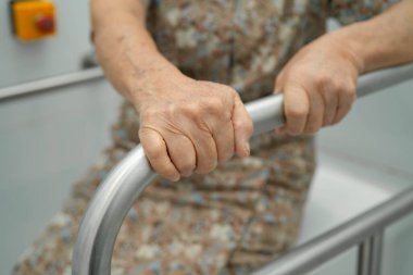 Asyalı yaşlı kadın hasta tuvalette tuvalet desteği kullanıyor..