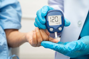 Diyabet tedavisinde kan şekeri seviyesini kontrol etmek için dijital glikoz ölçer kullanan Asyalı doktor.