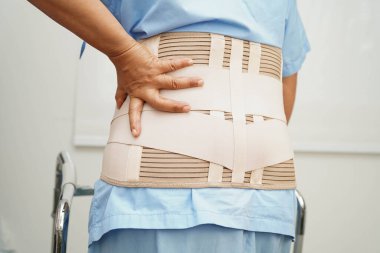 Bel ağrısı çeken Asyalı bir kadın. Hastanede yürüteç kullanıyor..