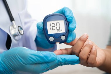 Diyabet tedavisinde kan şekeri seviyesini kontrol etmek için dijital glikoz ölçer kullanan Asyalı doktor.