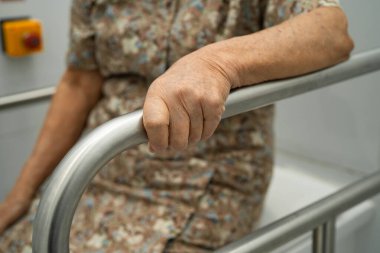 Asyalı yaşlı kadın hasta tuvalette tuvalet desteği kullanıyor..