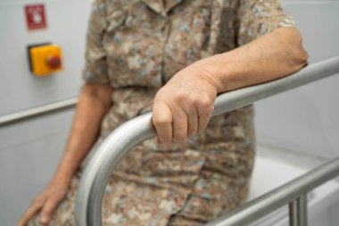 Asyalı yaşlı kadın hasta tuvalette tuvalet desteği kullanıyor..