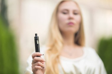 Vape genç. Yaz aylarında elektronik sigara sokakta onun elinde tutan bir kıyafeti içinde genç Sevimli beyaz kız.