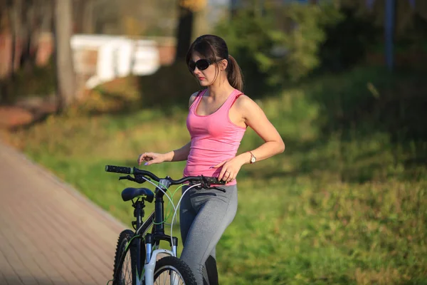 Όμορφη Κοπέλα Γυαλιά Ηλίου Και Αθλητικά Στέκεται Δίπλα Ένα Ποδήλατο — Φωτογραφία Αρχείου