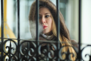 Vape hanım. Bir kürk ceket genç güzel kız sarışın elektronik bir sigara sigara ve kışın açık vintage ağ geçidi yakınında buhar puffs kapalı sağlar.